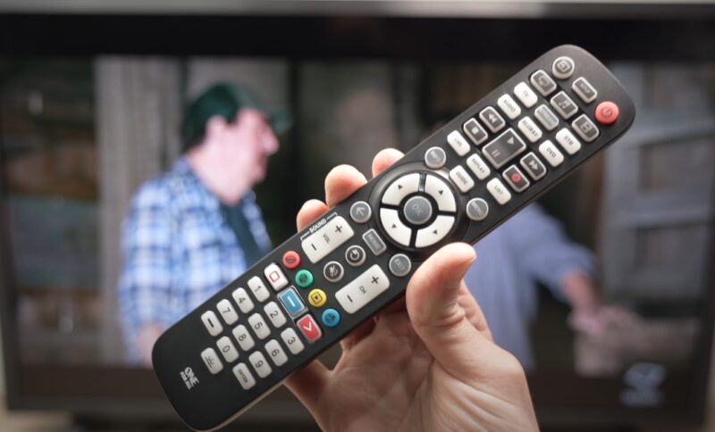 Close up photo of a human hand holding TV remote